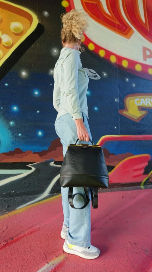 vrouw met zwarte Beizonder tas voor een graffiti muur